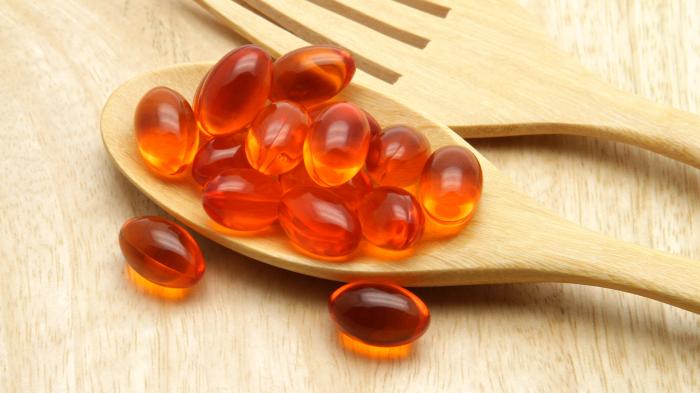 Деревянная ложка с капсулами рыбьего жира.