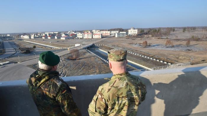 Двое солдат смотрят на военный полигон