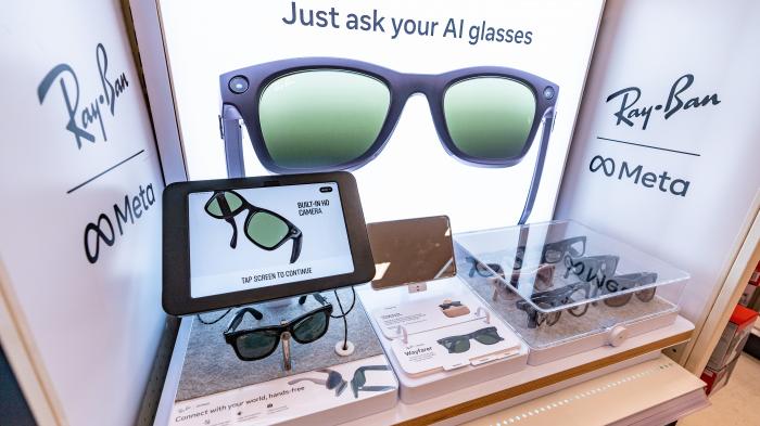 В магазине представлены умные очки Ray-Ban Meta с демонстрационным планшетом, информацией о продукте и рекламным слоганом «Просто спросите свои очки с искусственным интеллектом».