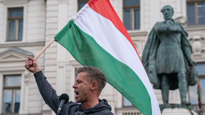 Мужчина с венгерским флагом перед зданием