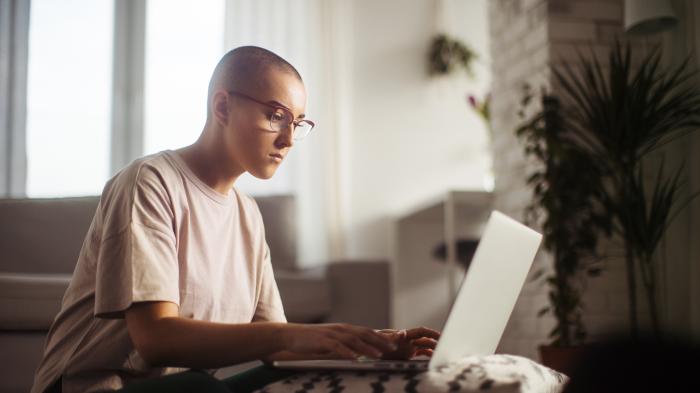 молодая женщина с волосами, которые только отрастают, работает за компьютером